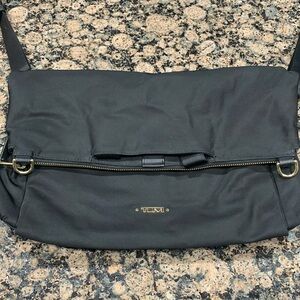 Tumi black folding crossbody with adjustable strap.